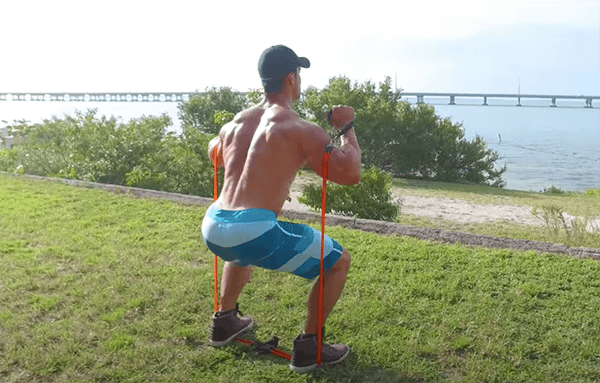 Un homme effectue des squats avec une bande élastique devant l