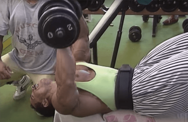 Mohamed Benaziza en train de faire du développé couché aux haltères à la salle de musculation.
